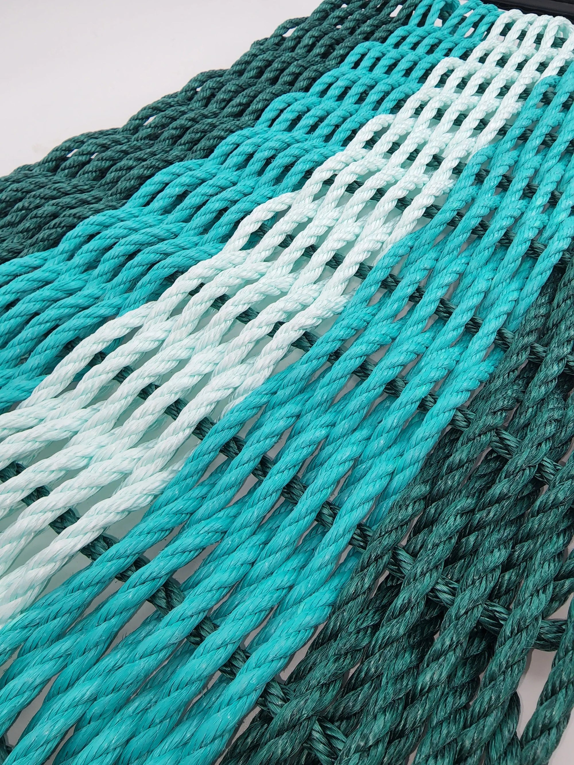 Handmade lobster rope mat in hunter green, teal, and seafoam colors