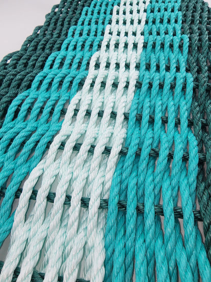 Handmade lobster rope mat in hunter green, teal, and seafoam colors
