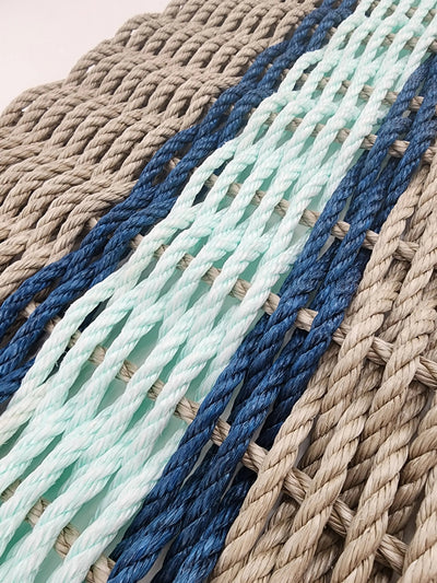 Handmade lobster rope door mat in tan with seafoam and navy blue accent colors