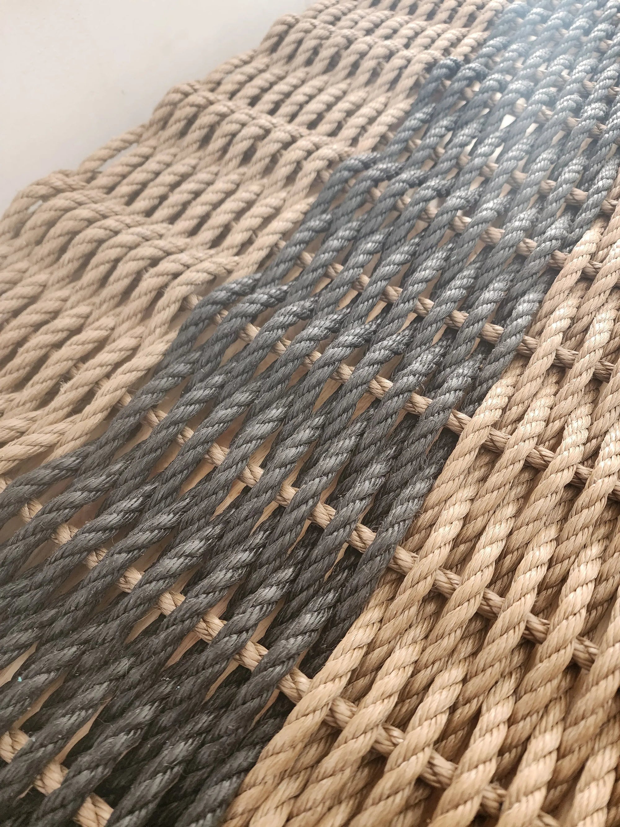 Brown and black handmade lobster rope mat on wooden floor