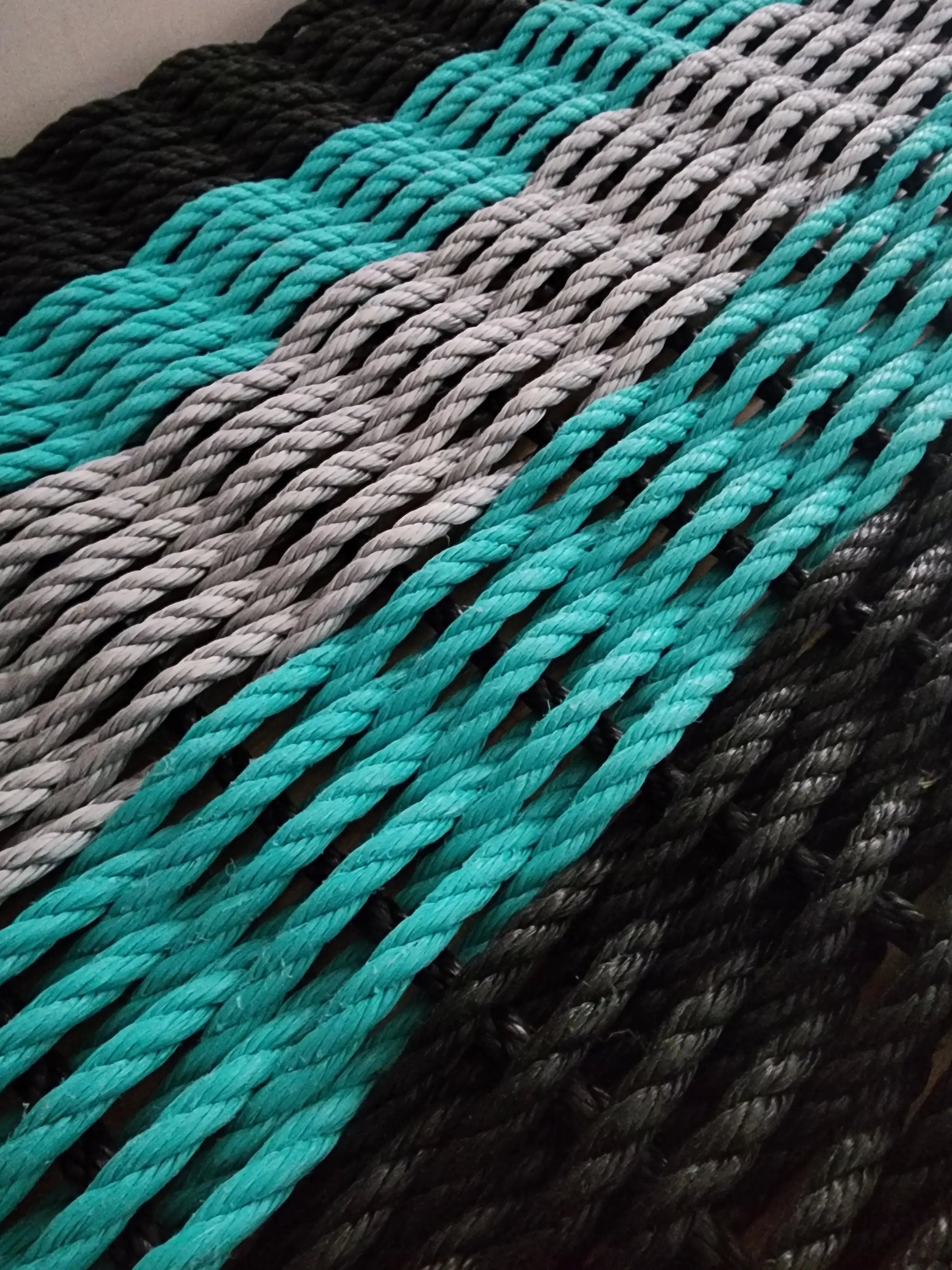 Five Stripe Rope Mat in Black, Teal, and Light Gray laid out on floor