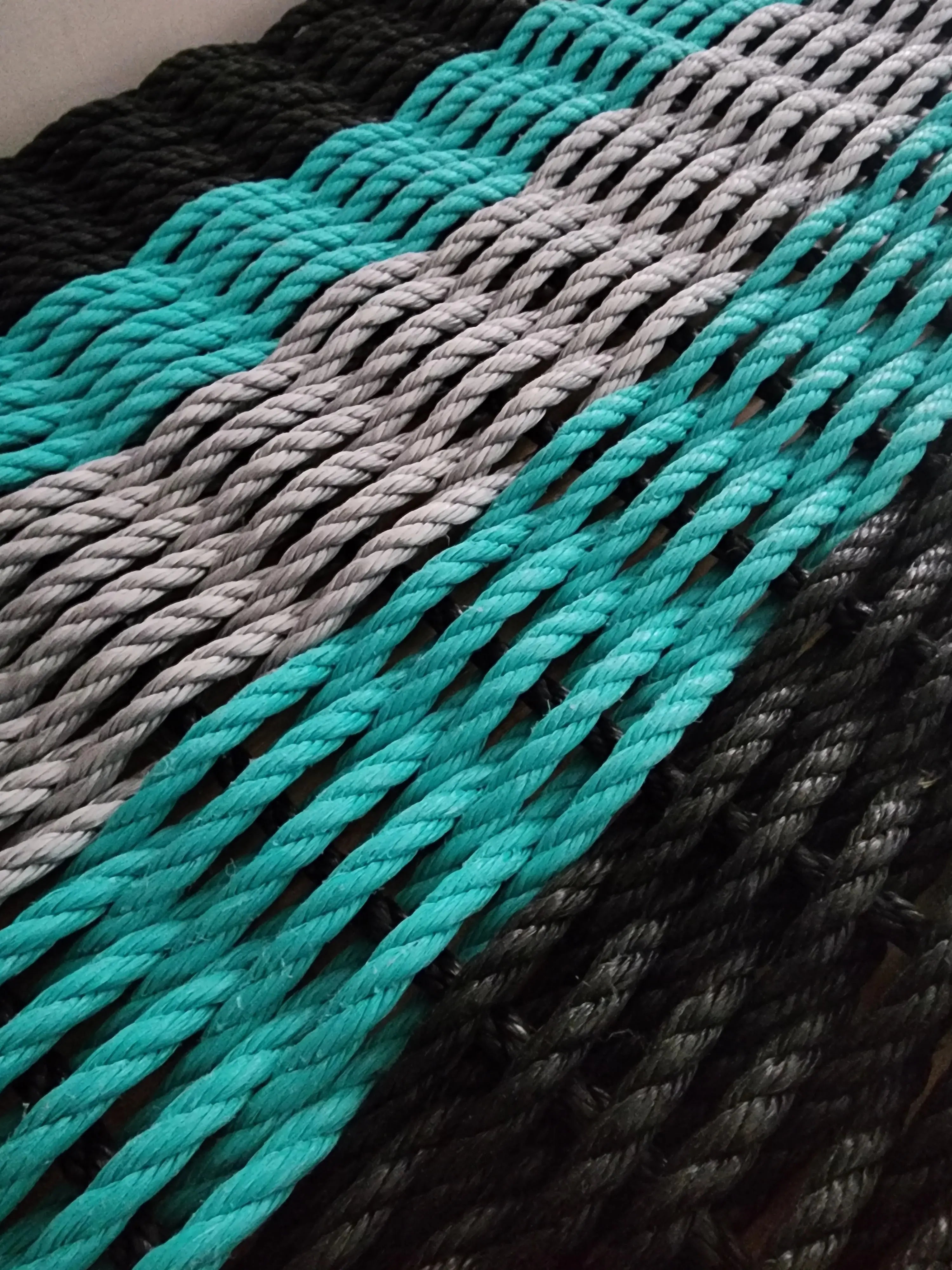 Five Stripe Rope Mat in Black, Teal, and Light Gray laid out on floor