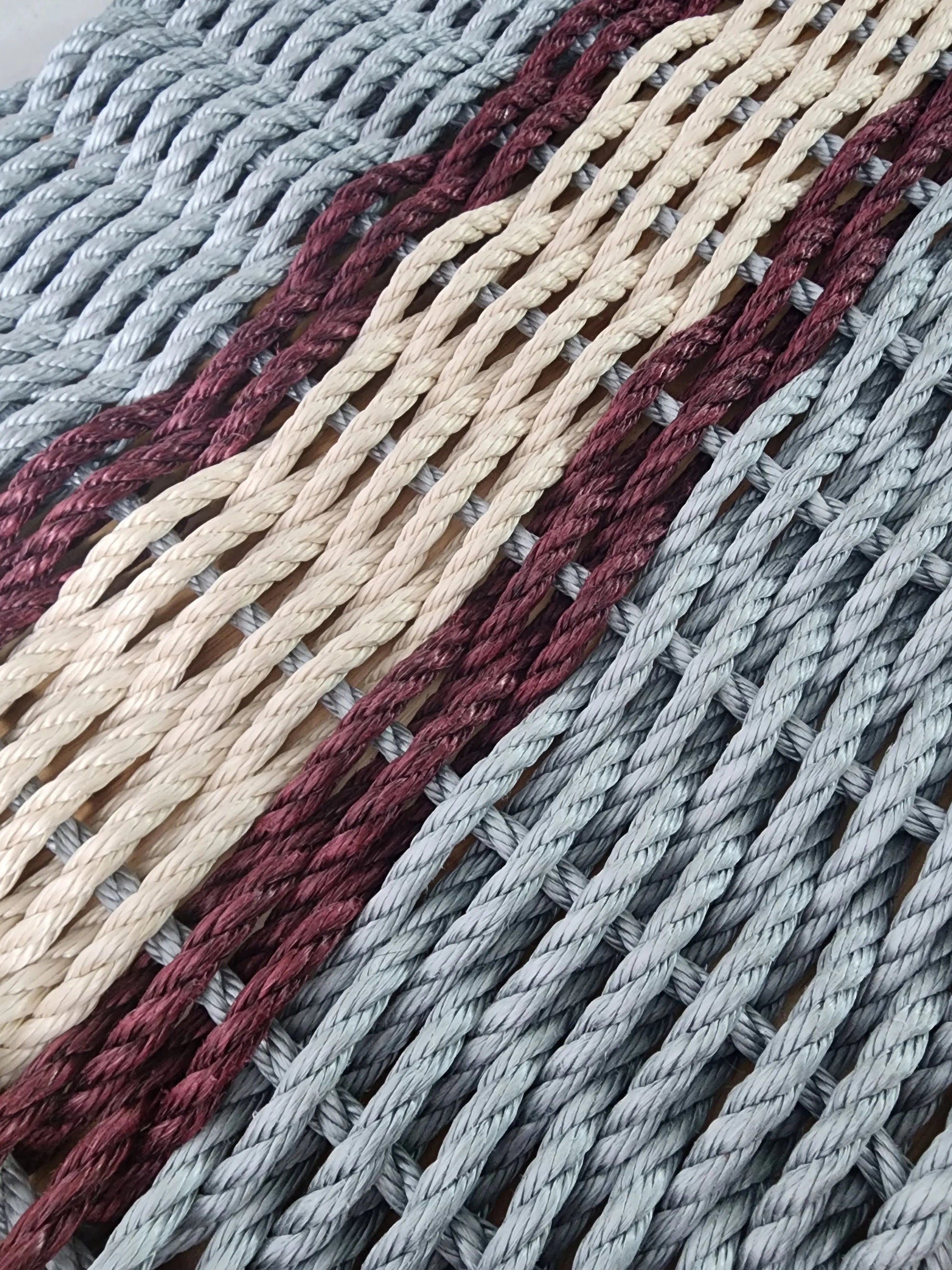 Light gray and light tan outdoor mat with burgundy accents made of polypropylene rope