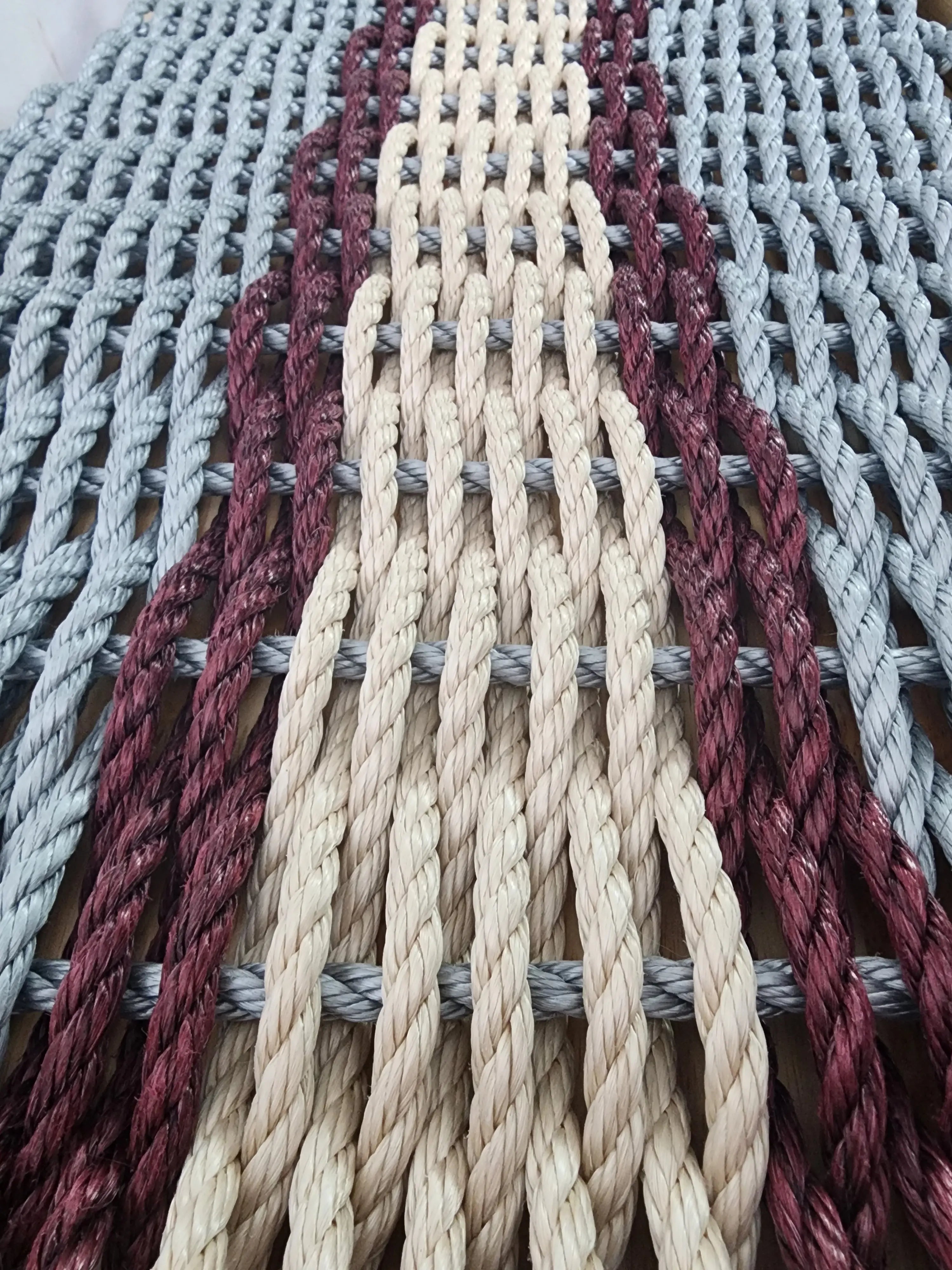 Light gray and light tan outdoor mat with burgundy accents made of polypropylene rope