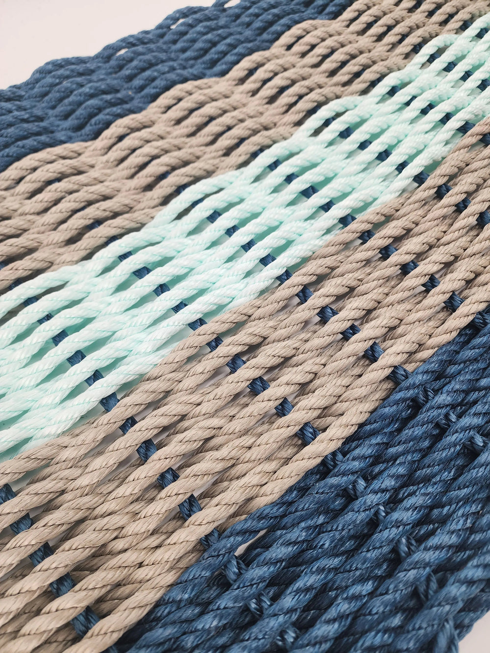 Five Stripe Rope Mat in navy, tan, and seafoam colors made from lobster rope