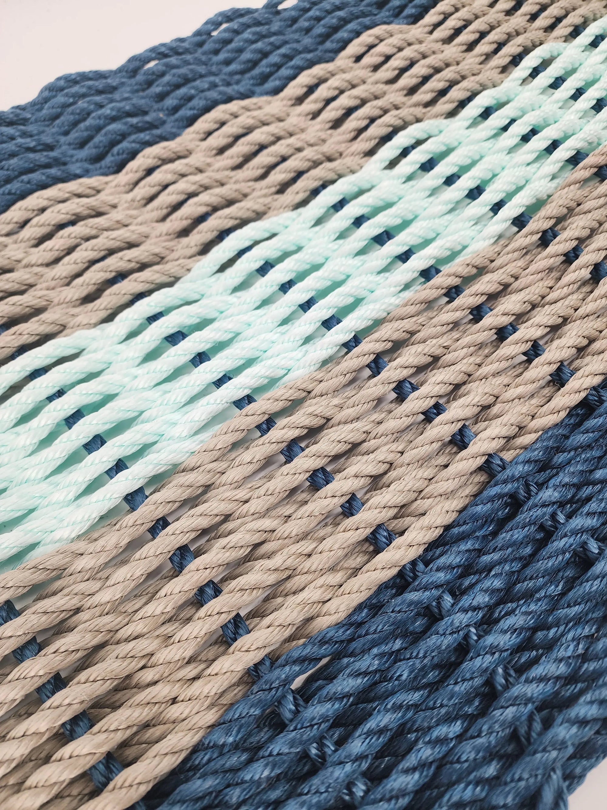 Five Stripe Rope Mat in navy, tan, and seafoam colors made from lobster rope