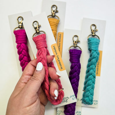 Brightly colored Macrame Braided Key Wristlets displayed draped over a wooden branch