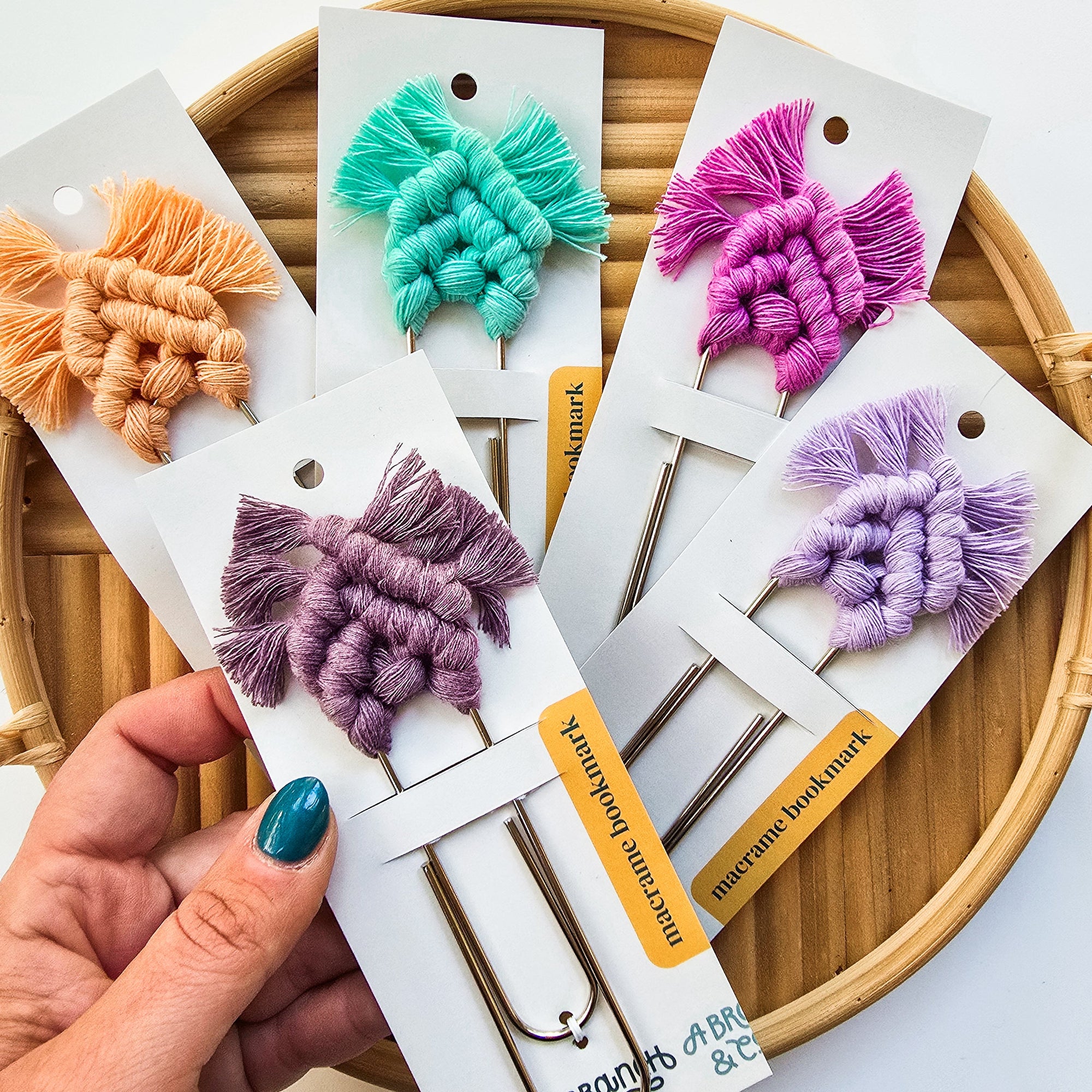 Soft pastel-colored macrame bookmarks arranged on a white backdrop