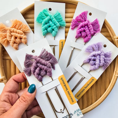 Soft pastel-colored macrame bookmarks arranged on a white backdrop