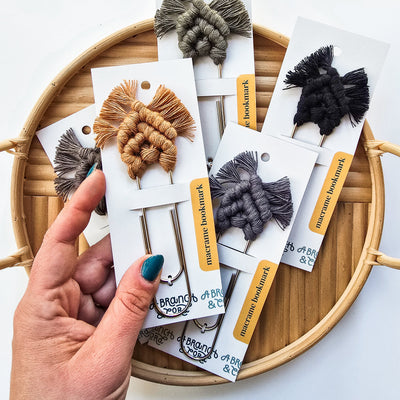 Neutral-toned macrame bookmarks laid out on a wooden surface with book edges visible
