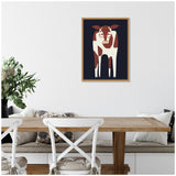 Framed minimalist canvas of a brown and white cow on a dark navy blue background hanging above a wooden dining table with white cross-back chairs and a vase of greenery.