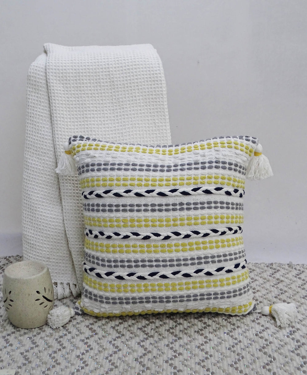 20 by 20 inches Throw Pillow with braided front and corner tassels on couch