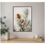 Framed canvas print depicting detailed pine branches with two brown pine cones against a soft, light background above a wooden surface with a vase and stacked books.