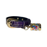 Purple crocodile-embossed leather collar with a gold buckle and a multicolored rhinestone-studded gold charm attached by a small ring.
