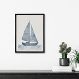 Framed print of a blue sailboat with textured sails and waves, hung on a white wall above a black cabinet with a small cactus in a black pot and stacked white books.