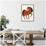 Stylized brown horse with a flowing dark mane and tail wearing teal glasses, centered on a white background within a wooden frame hung above a dining nook with white chairs and neutral cushions.