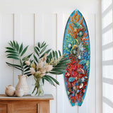 Surfboard-shaped wall art featuring underwater sea life with colorful coral and fish in shades of blue, orange, and red, mounted vertically on a white paneled wall.