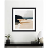 Abstract coastal landscape with black cliffs, beige sand, and a blue-gray sea under a cloudy sky, framed in black and hung on a white wall above a black console.