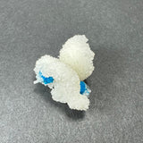 Cluster of bright blue cavansite balls partially enveloped by white stilbite crystals on a gray surface, showcasing contrasting texture and color.