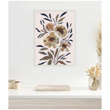 Framed canvas with large muted florals in soft beige, brown, and navy on light pink, hung above a white desk with dried flowers and small containers.