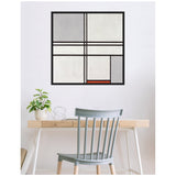 A framed abstract painting with black grid lines dividing gray, off-white, and a small red rectangle, hung above a minimalist wooden desk with a light gray chair and a potted plant.