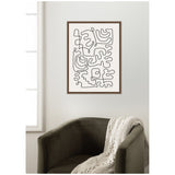 Black abstract connected line shapes on white canvas with a dark brown wood frame, hanging on a light wall above a dark olive armchair with a cream knitted throw.