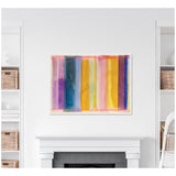 Abstract framed canvas with vertical watercolor stripes in purple, blue, yellow, pink, and orange hues, hanging above a white fireplace in a minimalist living room.