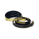 Black collar and leash set with a shiny yellow and gold textured finish, featuring gold-tone hardware and branded inner lining, displayed coiled on white background.