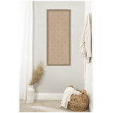 Vertical rectangular beige pinboard with a white lattice pattern and a brown frame, mounted on a light gray wall above a wicker basket and decorative vase with dried grasses.