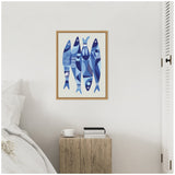 Wall art featuring four stylized blue sardines with varied geometric patterns framed in light wood above a rustic wooden bedside table holding a cup and books