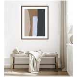 Abstract framed art with vertical torn paper strips in beige, brown, blue, and black hung above a wooden bench with a beige throw and an open book in a minimalist room.