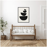 Minimalist living room with a wooden bench featuring white cushions, a round woven rug, a potted leafy plant, and a black framed art print of four stacked black semicircles on white background.