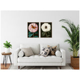 Two framed canvas prints above a white sofa, one with a pink flower and orange butterfly, the other with a white flower and black bee, all on dark backgrounds.