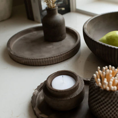 Set of brown ceramic items including a bowl, candle holder, and toothpick holder on a light surface.