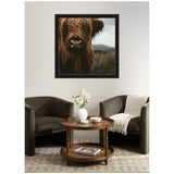 Framed close-up photo of a Scottish Highland calf with shaggy reddish-brown hair and a blurred outdoor background, hanging above a cozy seating area.