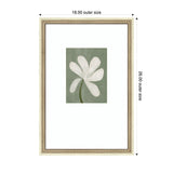 Framed art print of a white abstract floral with seven rounded petals on a muted green background, surrounded by a wide white matte and ornate gold frame, measuring 18x26 inches.
