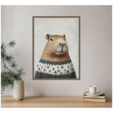 Framed canvas painting of a capybara wearing a green sweater decorated with white and brown snowflake patterns, set against a snowy light gray background.