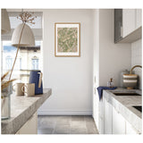 Modern minimalist kitchen with light gray countertops, white cabinets, a blue teapot, beige mugs, and a framed green and beige William Morris Windrush 1883 print on the wall.