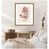 Minimalist framed print with red flower sketch and green-striped vase, titled 'Les Fleurs,' displayed above a wood cabinet in a neutral-toned bedroom scene.