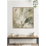 Abstract floral canvas with brushstrokes in muted olive, beige, and gray tones framed in light wood above a shelf holding a mug, books, and a white vase with greenery.