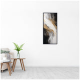 Tall abstract wall art with black, white, and gold swirls creating a flowing, marble-like texture, displayed in a thin black frame in a minimalist white room.