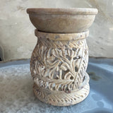 Carved soapstone essential oil burner in beige tones with intricate leafy pattern on cylindrical base, topped by a smooth, shallow bowl.