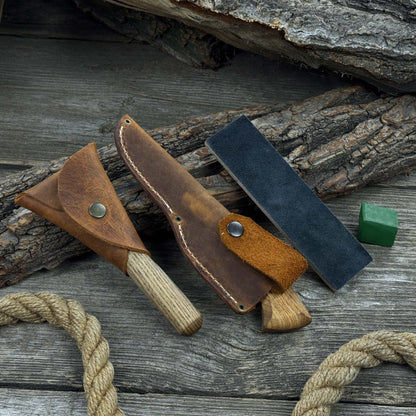 3-Piece Spoon Carving Tool Set with Leather Strop by Sharky Forged Steel Tools showing hook knife, sloyd knife, and leather strop on wooden surface