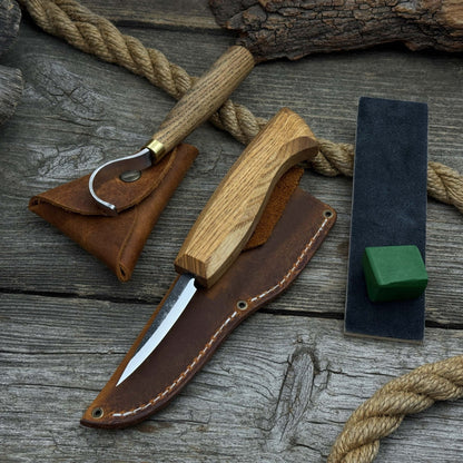 3-Piece Spoon Carving Tool Set with Leather Strop by Sharky Forged Steel Tools showing hook knife, sloyd knife, and leather strop on wooden surface