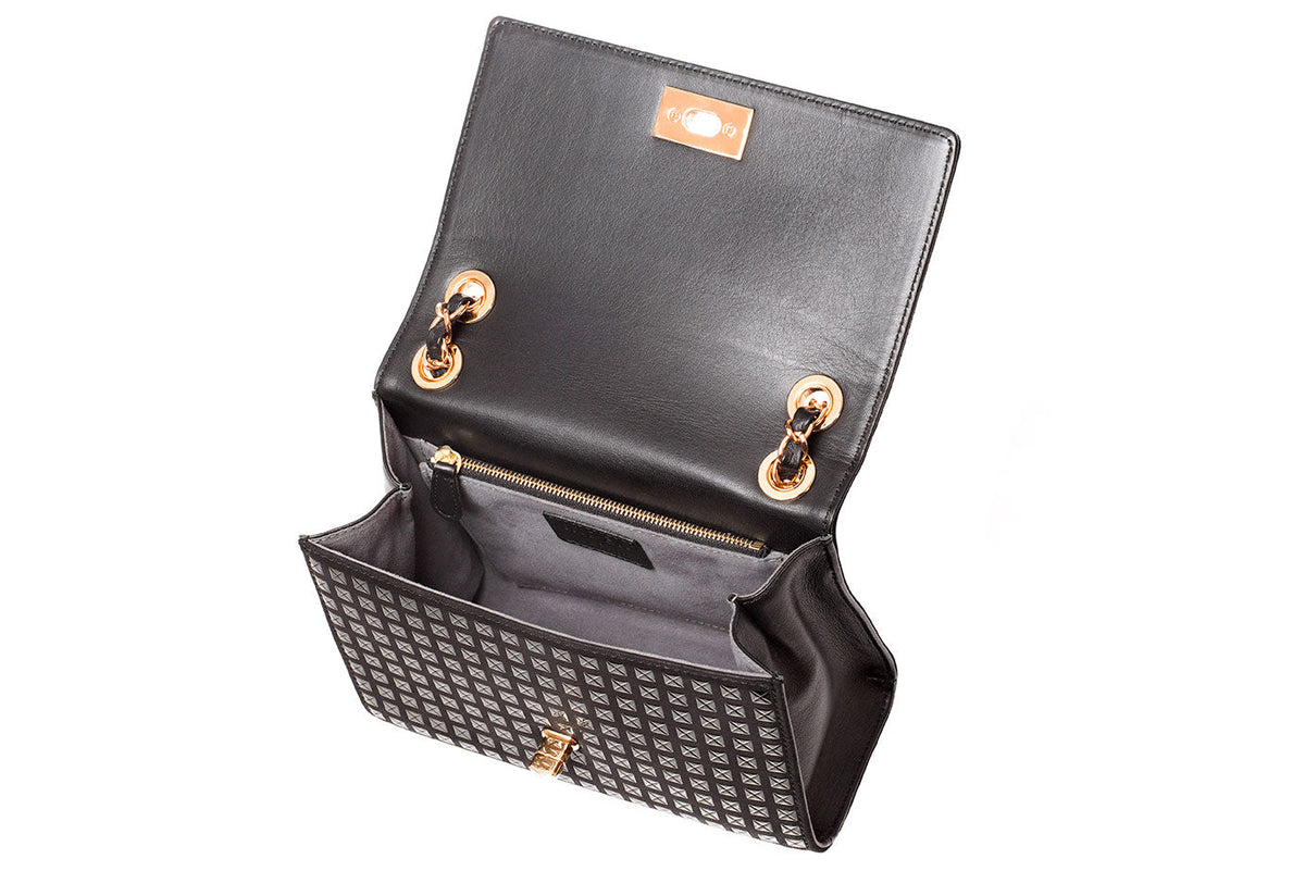 Open black shoulder bag with patterned front panel and gold-tone chain attachment points, showing black interior lining and magnetic closure flap.