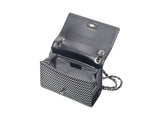 Black leather shoulder bag with a textured black and white front flap, open to show a gray fabric interior and a silver chain strap inside.
