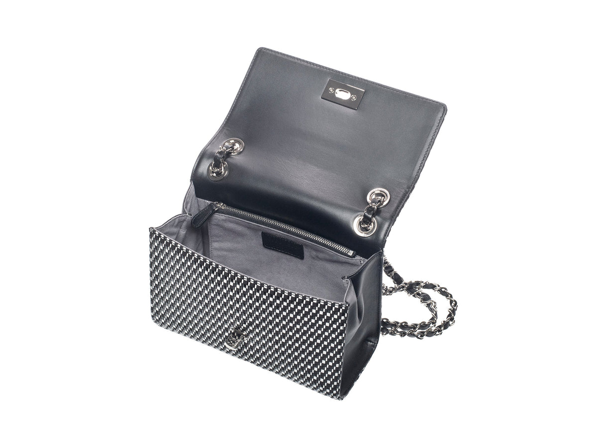 Black leather shoulder bag with a textured black and white front flap, open to show a gray fabric interior and a silver chain strap inside.