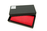 Red long wallet with a white flower lattice pattern, displayed inside a partially open black box with a white logo on the lid corner.