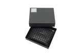 Large black key case with geometric stud pattern, resting in a matching black box with a silver emblem on the lid, shown from above.