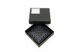 Black lacquered square tray with a raised interlocking circle pattern, presented inside a black box with a white decorative logo on the lid.